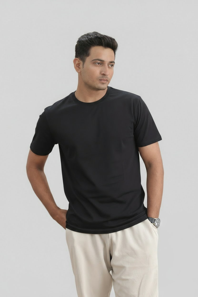 Man wearing a black t-shirt and light-colored pants on a gray background