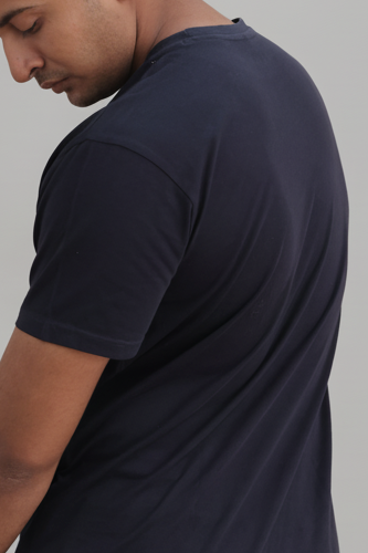 Man wearing a navy blue t-shirt and beige pants against a gray background