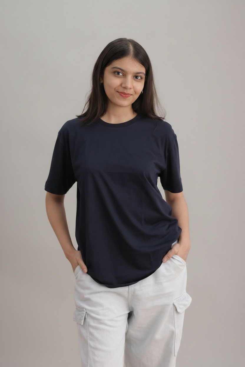 Woman wearing a navy blue t-shirt and light-colored pants against a plain background