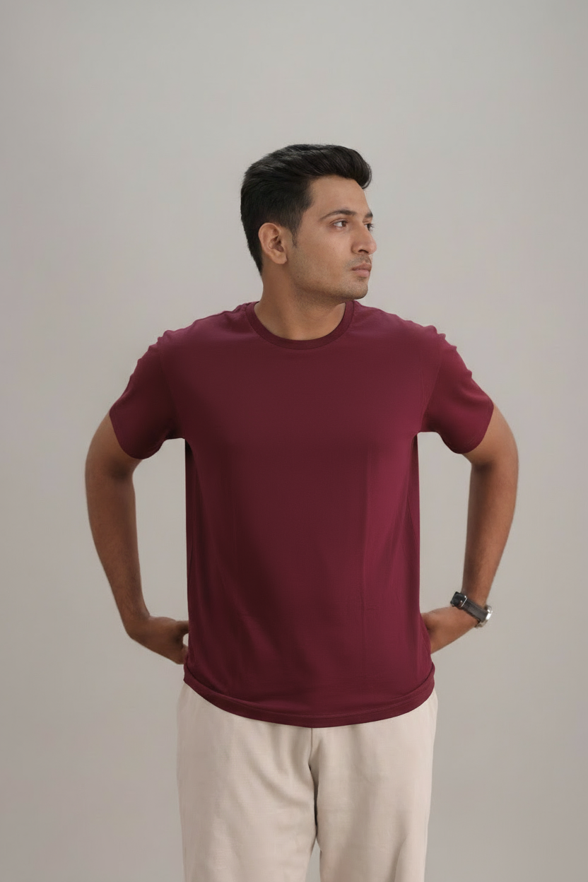 Man wearing a maroon t-shirt and beige pants against a plain background