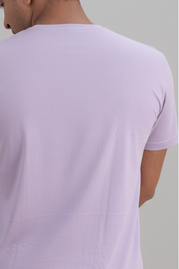 Person wearing a lavender t-shirt against a gray background